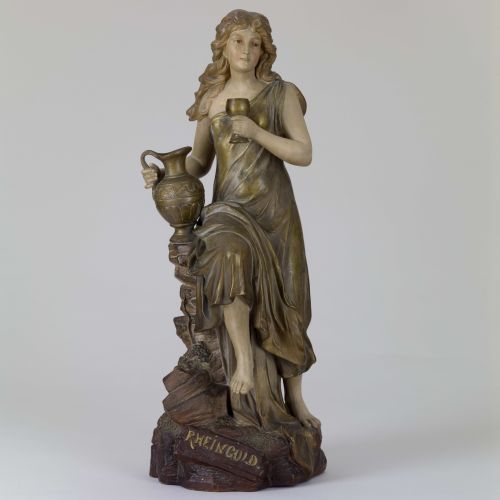 Auf den Mythos des Rheingoldes aus dem Nibelungenlied verweisen bei vorliegendem Bildwerk primär die Bezeichnung auf der Terrainplinthe sowie der goldene Schimmer der Plastik, wodurch an den versenkten Schatz des Mythos' erinnert wird.