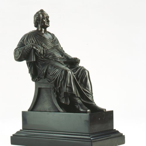 Es handelt sich um eine verkleinerte Ausführung der 1838 von Pompeo Marchesi geschaffenen Denkmalfigur, die in Frankfurt a. M. ihre Aufstellung fand. Das aus Marmor ausgeführte Standbild wurde im Zweiten Weltkrieg zerstört