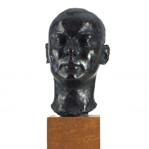 Kurt Edzards Bronzeplastik zeigt Kopf und Hals eines jungen Mannes mit kurzen Haaren in Lebensgröße. Das Werk ist K E signiert, nicht datiert und mit dem Stempel des Pariser Gießers Carvillani versehen