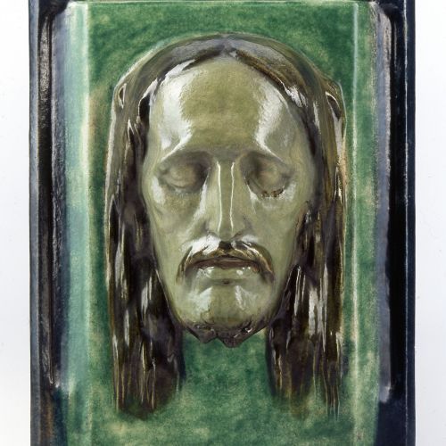 Georg Graseggers Keramik-Relief zeigt eine polychrom staffierte Darstellung des Antlitz Christi mit geschlossenen Augen.